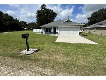Charming home featuring a well-manicured lawn, a two-car garage and mailbox at 10470 Sw 132Nd Ct, Dunnellon, FL 34432