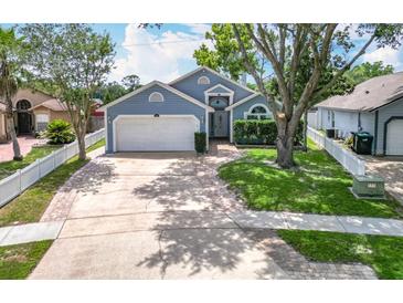 Charming blue house with a well-manicured lawn, mature trees and a two-car garage at 2641 Delcrest Dr, Orlando, FL 32817