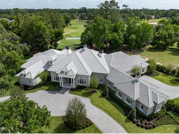 Stunning aerial view of a large luxury home with a patterned driveway and meticulously manicured lawn and gardens at 8707 Nw 31St Lane Rd, Ocala, FL 34482