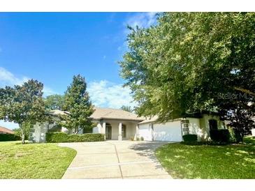 Charming single-story home featuring lush landscaping, a large driveway, and a welcoming entrance at 11315 Cypress Shore Ct, Clermont, FL 34711