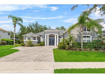 Charming single-story home with a brick driveway, manicured lawn, and lush landscaping at 4013 Greystone Dr, Clermont, FL 34711