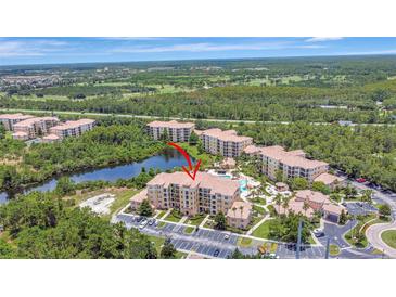 Stunning aerial view of condos with a luxurious community pool surrounded by lush greenery and a peaceful lake at 8601 Worldquest Blvd # 3404, Orlando, FL 32821