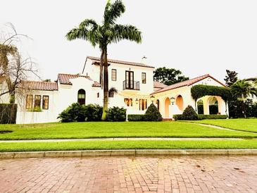 Charming white two-story home featuring a red tile roof and a lush green lawn with a mature palm tree at 1234 W Ivanhoe Blvd, Orlando, FL 32804