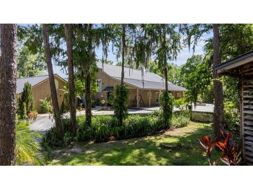 Charming home with wood siding, metal roof, lush landscaping, and mature trees providing shade and privacy at 13450 E Lake Mary Jane Rd, Orlando, FL 32832