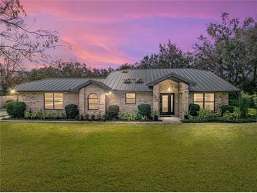 Brick house with metal roof, landscaping, and a large yard at 3703 White Oak Ct, Lake Wales, FL 33898