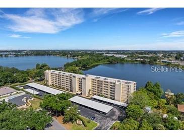 Scenic aerial view of a waterfront apartment complex surrounded by lush greenery at 700 Mirror Nw Ter # 403, Winter Haven, FL 33881