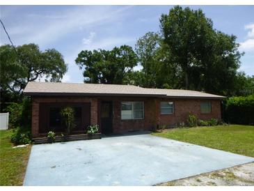 Charming single-story brick home with a well-maintained lawn and mature trees under a sunny blue sky at 112 Bishop St, Auburndale, FL 33823