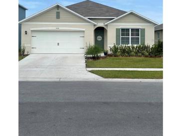 Charming single-story home with a well-manicured lawn, a two-car garage, and neutral paint at 1414 Fox Squirrel Dr, Davenport, FL 33897