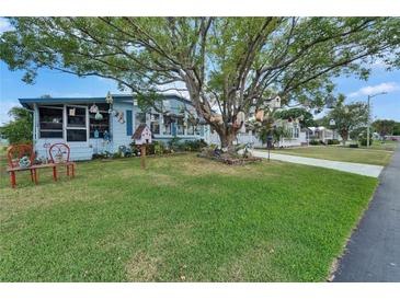 Charming home with a lush lawn, mature tree decorated with birdhouses, and cozy outdoor seating at 1575 Longbow Dr, Lakeland, FL 33810