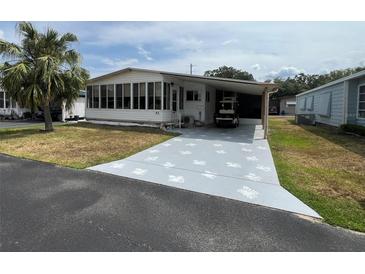 Charming single-story home featuring a covered carport, a palm tree, and a screened front porch at 2055 S Floral Ave # 45, Bartow, FL 33830