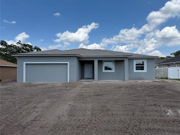 Charming single-story home featuring a grey exterior, attached garage, and a well-manicured front yard under a partly cloudy sky at 498 Big Sioux Ct, Kissimmee, FL 34759