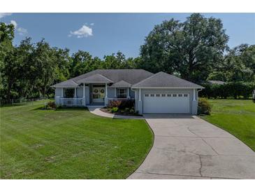 Charming single-story home featuring a well-manicured lawn, white picket fence, and an attached two-car garage at 5427 Orange Valley Dr, Lakeland, FL 33813