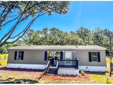 Charming gray home with a manicured lawn, updated windows, and a welcoming front porch at 7005 Dove Meadow Trl, Lakeland, FL 33810