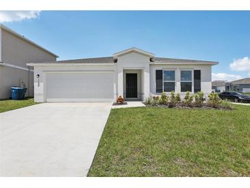 Charming single-story home featuring a two-car garage, well-manicured lawn, and modern architectural details at 3528 Dahlia Dr, Haines City, FL 33844