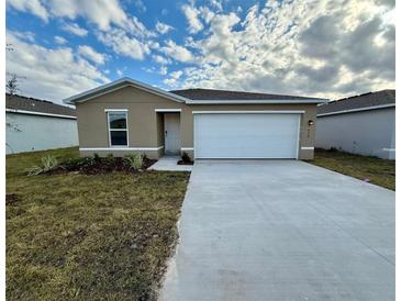 Tan one-story house with a two-car garage and newly landscaped yard at 1639 Texas Ave, Sumterville, FL 33585