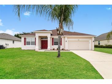 Single-story home with red door, two-car garage, and landscaped lawn at 5634 Moon Valley Dr, Lakeland, FL 33812