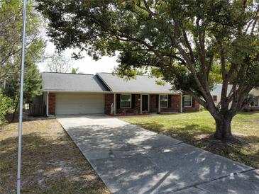 Charming single-story brick home features a two-car garage and a spacious front yard with mature shade tree at 1223 Lawrence Ave, Deltona, FL 32725