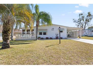Charming single story home with well-maintained lawn and tropical landscaping at 906 Beechwood Ave, Lady Lake, FL 32159
