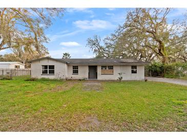 Single-story home with a white painted brick exterior, a lawn and mature trees at 3800 Levins Rd, Mulberry, FL 33860