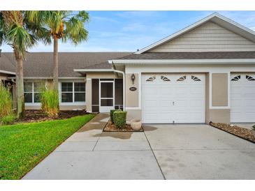 Inviting home exterior features a well-manicured lawn and attached two-car garage at 26922 White Plains Way, Leesburg, FL 34748