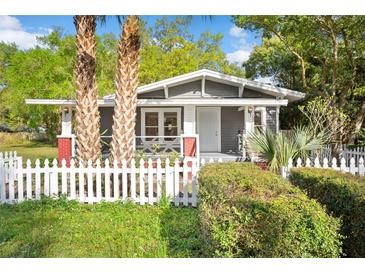 Charming home with gray siding, red brick accents, a white picket fence, and mature landscaping at 1309 Sanford Ave, Sanford, FL 32771