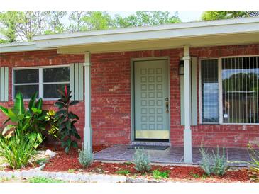 Charming brick home featuring a stylish front door, tiled porch and well maintained landscaping at 5801 Poinciana Ave, Lakeland, FL 33809