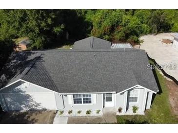 Aerial view of a gray house with a gray shingle roof and an attached two-car garage at 626 Nardello Dr, Deltona, FL 32725