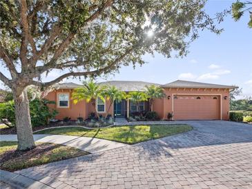 One-story home with orange exterior, landscaped yard, and paver driveway at 112 Sevilla Ct, Poinciana, FL 34759