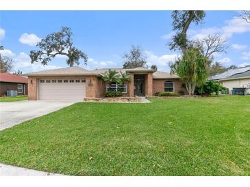 Charming single-story brick home with a lush lawn, mature trees, and attached two-car garage at 928 George Hecker Dr, South Daytona, FL 32119