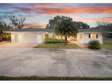 White single story home with attached garage, palm trees, and large driveway at 1045 Carter Rd, Deland, FL 32724