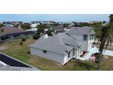 The back of the home features a well manicured lawn, brick border, and the rear elevation of the two-story home at 105 Barrier Isle Dr, Ormond Beach, FL 32176