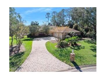 Single-story home with a paved driveway and lush landscaping at 56 Winding Creek Way, Ormond Beach, FL 32174