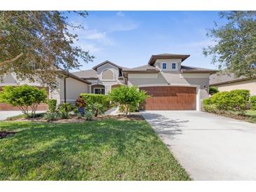 Tan two-story house with brown garage door and lush landscaping at 3238 Bailey Ann Dr, Ormond Beach, FL 32174