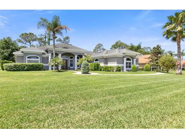 Gray house with lush lawn, palm trees, and walkway at 1068 Hampstead Ln, Ormond Beach, FL 32174