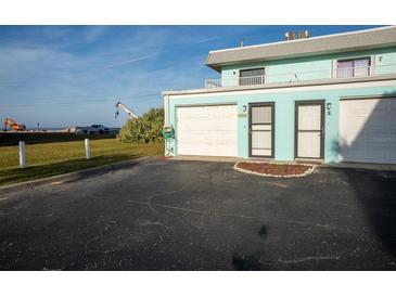 Ground level view of a teal colored building with attached garage and entrance at 2850 Ocean Shore Blvd # 8, Ormond Beach, FL 32176