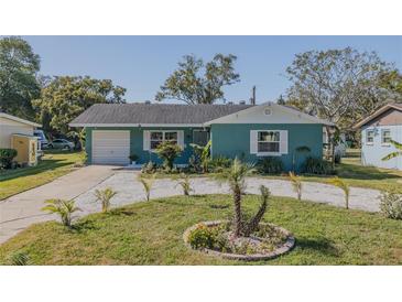 Cute teal house with a well-manicured lawn and circular flowerbed at 328 Dubs Dr, Holly Hill, FL 32117