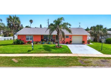 Charming single-story home with vibrant coral exterior, well-manicured lawn, and inviting curb appeal at 100 Lynnhurst Dr, Ormond Beach, FL 32176