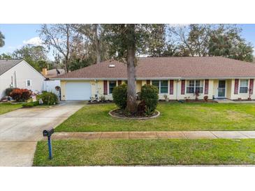 Charming single-story home featuring a well-manicured lawn, red shutters and an attached garage at 1054 W Samms Ave, Port Orange, FL 32129