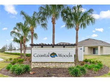 Coastal Woods community entrance sign featuring lush landscaping and swaying palm trees at 806 Armenia Ct, New Smyrna Beach, FL 32168