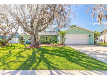 Charming single-story home featuring a manicured lawn, mature trees, and a welcoming two-car garage at 906 Timberwood Dr, Port Orange, FL 32127