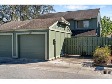 View of the detached single car garage and green wooden fence gate at the front of the townhome at 128 Pine Cone Trl, Ormond Beach, FL 32174