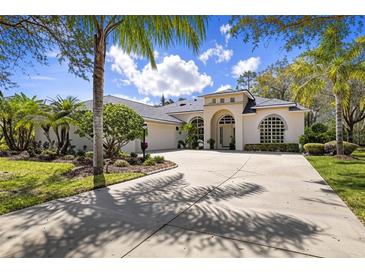 Elegant home featuring a large driveway, arched entryway, lush landscaping, and beautiful windows on a sunny day at 1432 Kinnard Cir, Ormond Beach, FL 32174