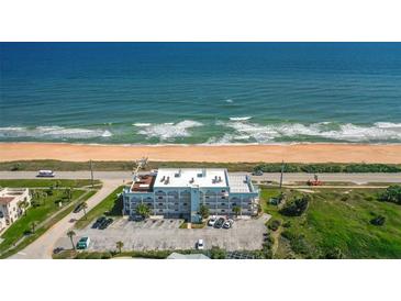 An aerial view shows the condo building, sandy beach, and ocean view at 3390 Ocean Shore Blvd # 4020, Ormond Beach, FL 32176
