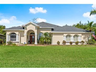 Beautiful single-story home featuring a well-manicured lawn and a welcoming red-door entryway at 3428 Rexford Cir, Ormond Beach, FL 32174