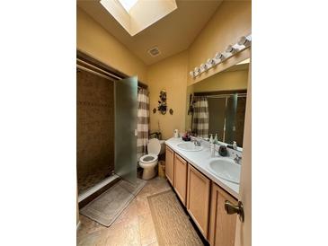 Bright bathroom features a skylight, walk-in shower, and double sink vanity at 105 Cattail Ct, Kissimmee, FL 34743