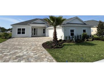 Beautiful single Gathering home with manicured lawn and charming front yard with a paver driveway and a palm tree at 1010 Megano Blvd, Deland, FL 32724