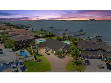 Stunning aerial view of waterfront home with swimming pool, lush landscaping, and boat docks at sunset at 2924 River Point Dr, Daytona Beach, FL 32118