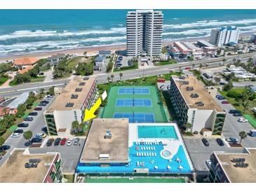 Aerial view of beachfront condo complex featuring a swimming pool, tennis courts, and ocean views at 1441 N Atlantic Ave # 211, Daytona Beach, FL 32118