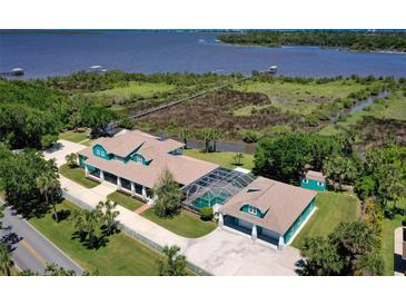 Stunning aerial view of estate home overlooking waterfront with dock and green landscape at 2189 Old Dixie Hwy, Ormond Beach, FL 32174