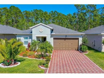 Charming single-story home with a well-manicured lawn, a brick driveway, and a two-car garage at 5635 Estero Loop, Port Orange, FL 32128